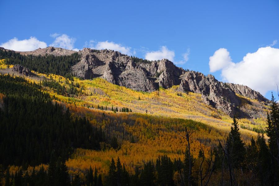 Sunlit rocky ridge over aspen-covered slopes